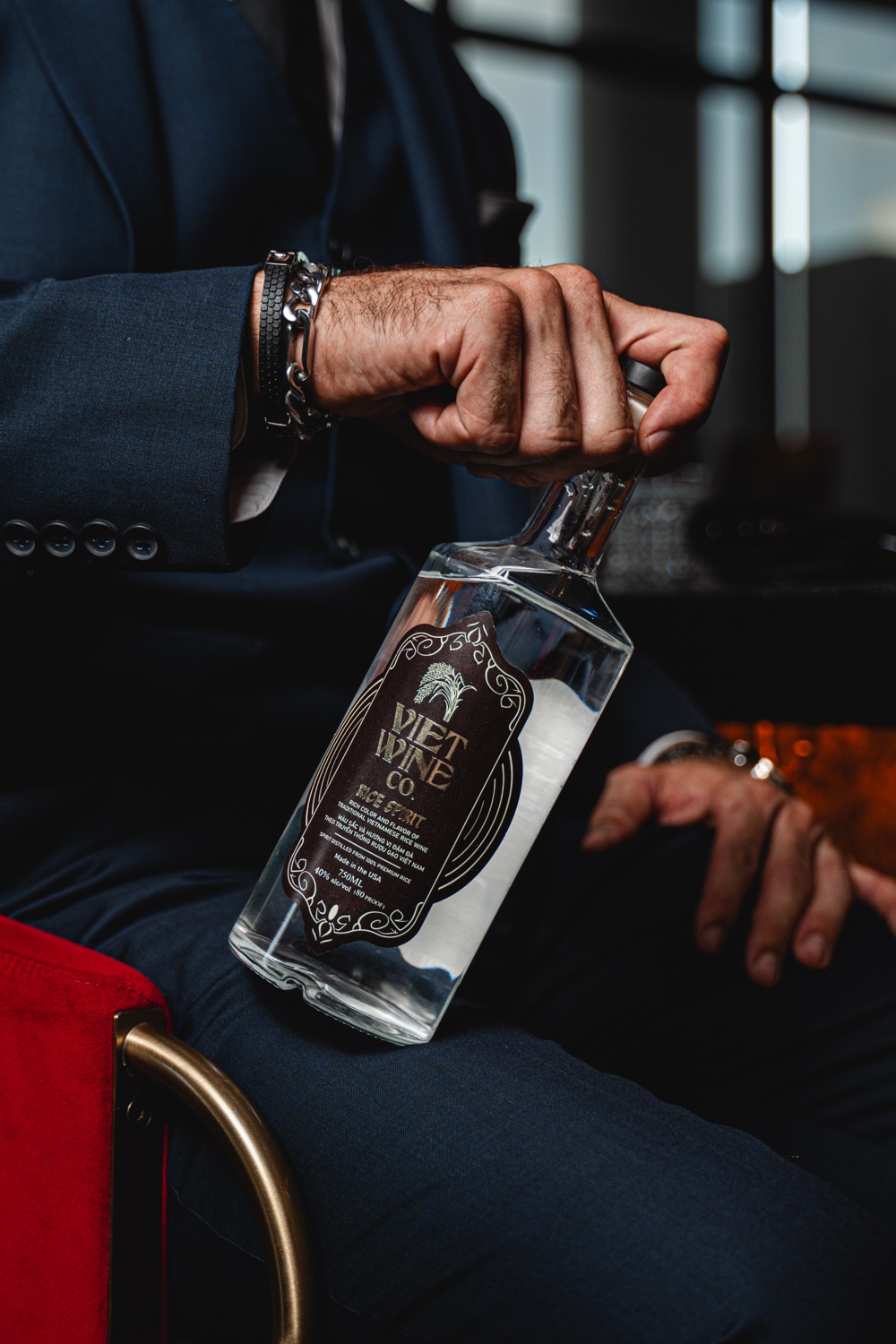 A man in a navy suit opening a bottle of Viet Wine Co. Rice Spirit